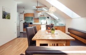 Appartement im Bioweingut Jakob, © Bioweingut Jakob Moderne Küche mit Holzmöbeln und Esstisch in einem Appartement.