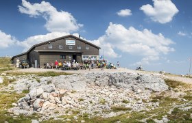 Fischerhütte auf 2049m, © WA/Franz Zwickl Fischerhütte auf dem Schneeberg mit Wanderern und blauem Himmel.