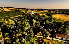 Kellergasse mit Rochusberg, © Robert Herbst Landschaft mit Feldern, Bäumen und einer kleinen Kirche in der Mitte.