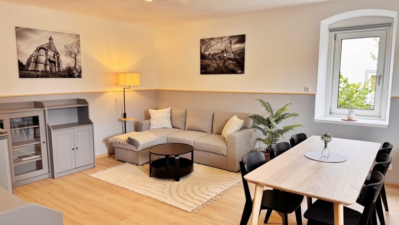 WohnEssbereich, © Christoph Menhofer Moderner Wohn-Essbereich mit grauem Sofa, Esstisch und Pflanzen.