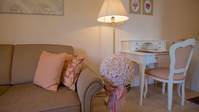 Rosenromantik, © www.wachaufoto.at Gemütliches Wohnzimmer mit Sofa, Schreibtisch und Blumenarrangement.