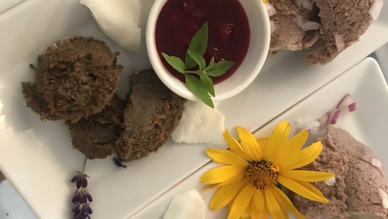 Heurigenjause, © Monika Pölzer Platten mit Aufstrichen, gelben Blumen und roten Soßen in kleinen Schalen.