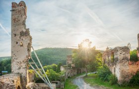 Burg Gars, © Reinhard Podolsky Ruinen der Burg Gars bei Sonnenuntergang mit bewaldeten Hügeln im Hintergrund.