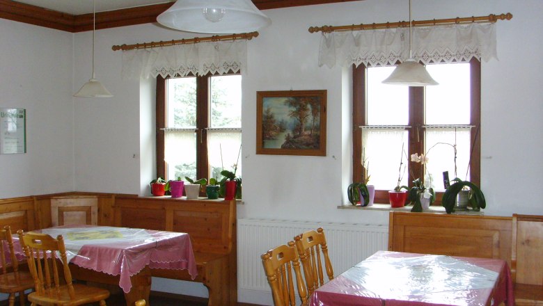 Privatzimmer Eder, © Eder Gemütlicher Raum mit Holzmöbeln, Tischdecken und Pflanzen auf der Fensterbank.