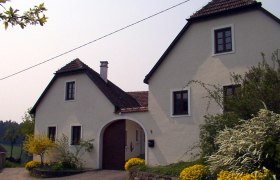 Haus, © Grünfelder Ein weißes Landhaus mit braunem Dach und Garten.