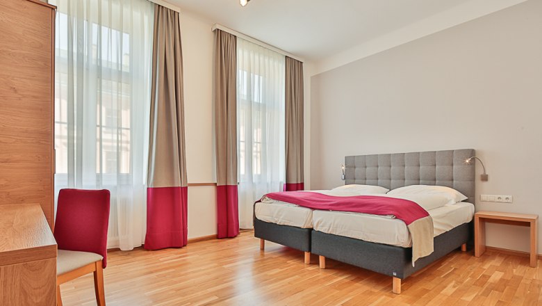 Hotel Unter den Linden Zimmer 104, © Hotel Unter den Linden Helles Hotelzimmer mit Doppelbett, Schreibtisch und Stuhl.