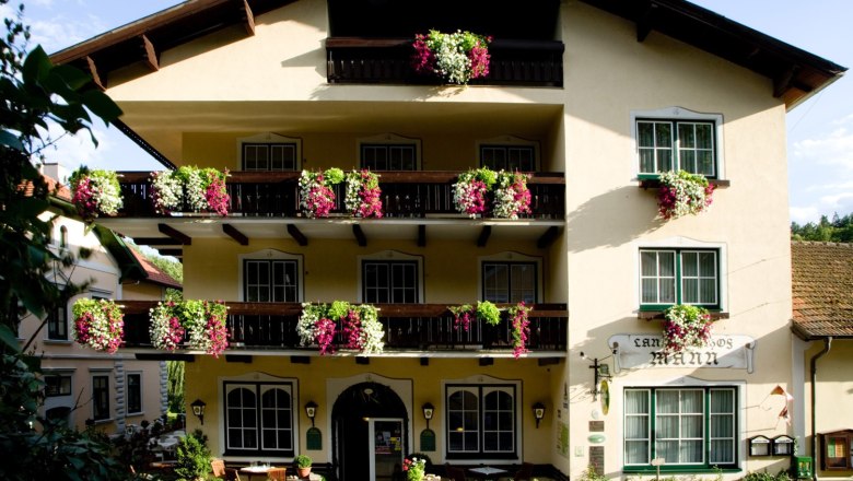 Hotel Restaurant Landgasthof Mann, © Hotel Restaurant Landgasthof Mann Fassade eines traditionellen Gasthauses mit Balkonen voller Blumen.