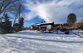 Belle Air Lodge im Winter, © Christoph Gierlinger Winterlandschaft mit einem Haus im Schnee, umgeben von Bäumen und blauem Himmel.