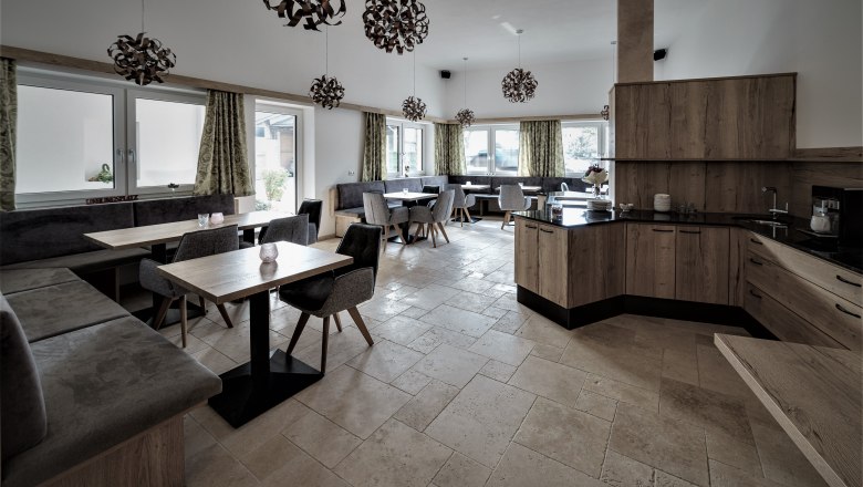 Fruehstuecksraum, © Maria Harrauer Moderner Frühstücksraum mit Holzmöbeln, grauen Polstern und dekorativen Lampen.