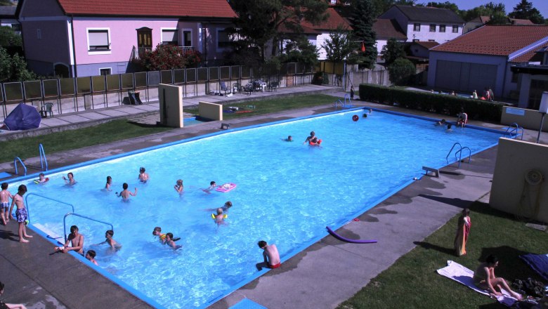 Weinbergbad Göttlesbrunn, © Gemeinde Göttlesbrunn Ein Freibad mit mehreren Menschen im Wasser und auf der Liegewiese.