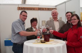 Edelbrennerei Bernhard & Sabine Biegl, © Edelbrennerei Bernhard & Sabine Biegl Gruppe von fünf Personen stößt mit Gläsern an einem Tisch an.