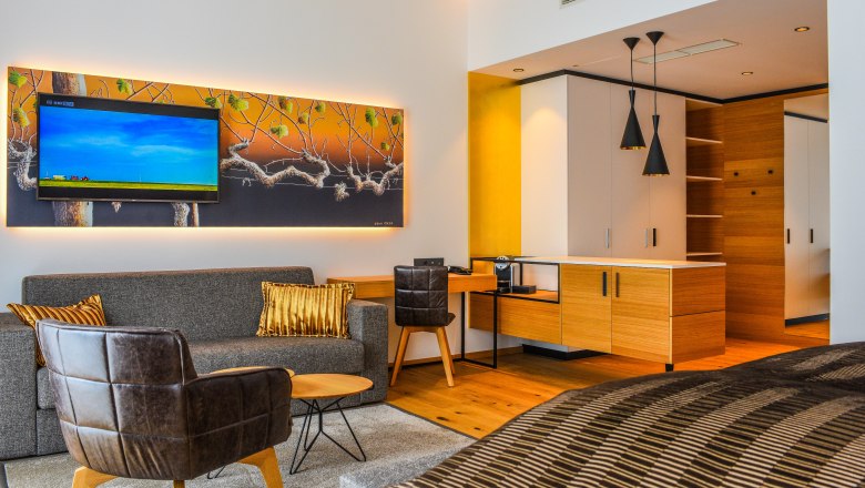 Suitebeispiel im Klinglhuber, © Franz Klinglhuber GmbH Moderne Hotelsuite mit Sofa, Sessel, TV und Küchenzeile.