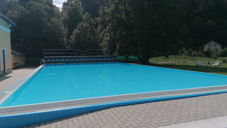 foto-bad-7, © Gemeinde Gutenstein Ein leerer Swimmingpool im Freien, umgeben von Bäumen und einem Gebäude.