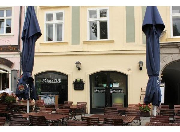 Siegl´s Schanigarten, © Siegl´s Pub - Simone Pichler Außenansicht eines Pubs mit leeren Tischen und geschlossenen Sonnenschirmen.