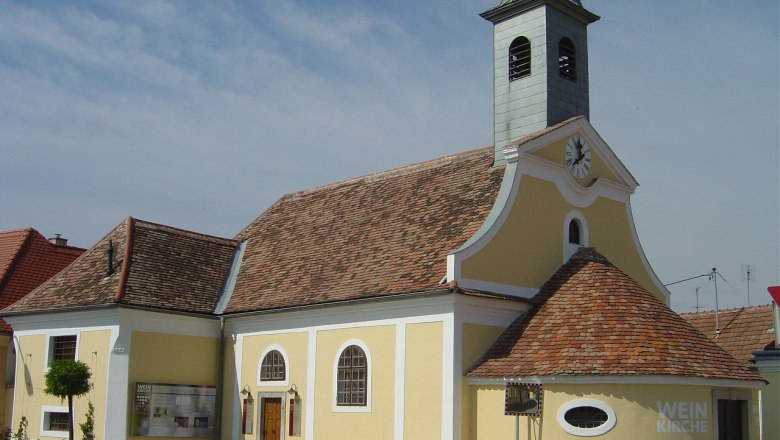 Weinkirche Jetzelsdorf, © Marktgemeinde Hhaugsdorf Gelbe Kirche mit Uhrturm und Schriftzug 'Weinkirche'.