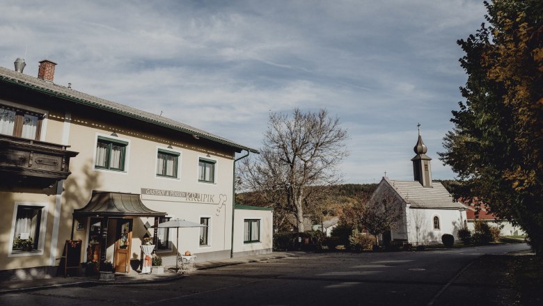 Gasthof in Steinbach bei Nagelberg, © Niederösterreich Werbung/Rita Newman Gasthof und Kirche in Steinbach bei Nagelberg, umgeben von Bäumen und blauem Himmel.