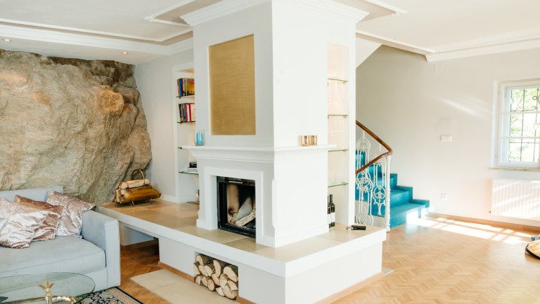 villa_schonthal-28_2, © Julius Hirtzberger Wohnzimmer mit Kamin, Felsenwand, blauer Treppe und Holzboden.