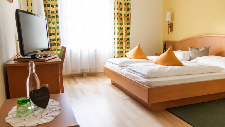 Weinbergzimmer, © Weinberghof Ilkerl Gemütliches Hotelzimmer mit Doppelbett, Fernseher und Vorhängen.