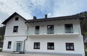 Privatzimmer Strasser, © Wiener Alpen Zweistöckiges weißes Haus mit Balkon und blauen Himmel im Hintergrund.