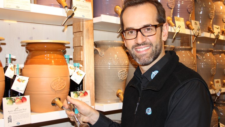 Gut beraten bei Vom Fass, © Harald Hoffmann-Tombor Ein Mann füllt eine Flasche aus einem großen Keramikfass bei Vom Fass.