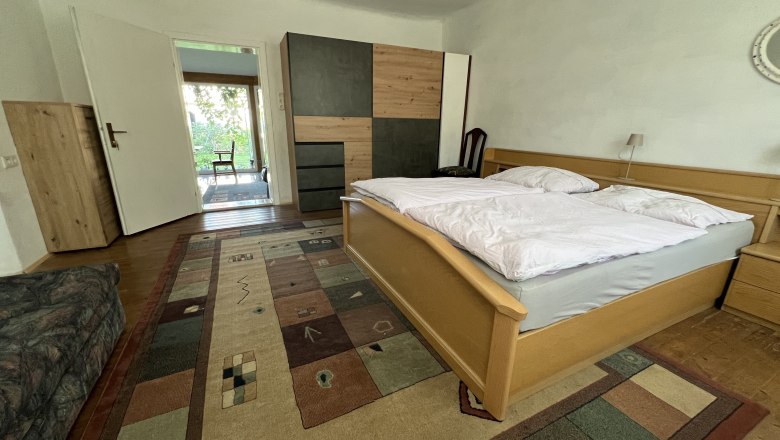 Doppelzimmer, © Gästehaus Weinwurm Schlafzimmer mit Doppelbett, Teppich und Schrank.