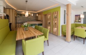 Verkostungsraum im Winzerhof, © Winzerhof Englmayer Moderner Verkostungsraum mit Holztischen und grünen Polstermöbeln.