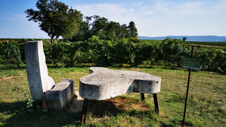 Ausruhen und die Landschaft genießen, © Weinstraße Weinviertel Steinbank und Tisch in einem Weinberg mit Schild 'Geheimtipp'.