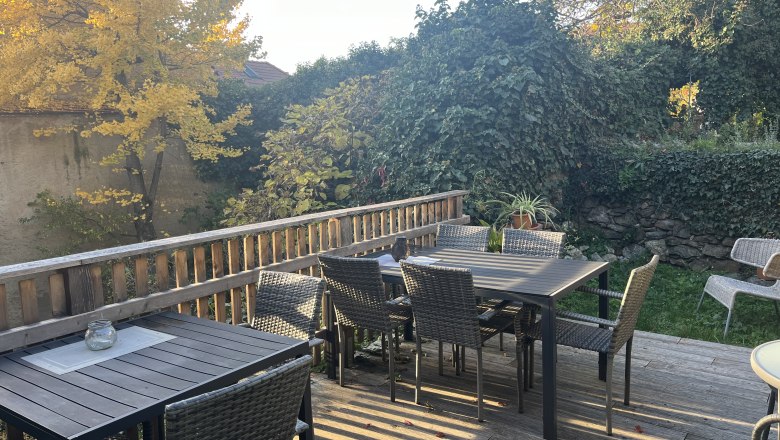 Pension Altes Rathaus in Dürnstein, © Familie Fürtler Terrasse mit Holztischen und Stühlen, umgeben von herbstlichen Bäumen und Pflanzen.