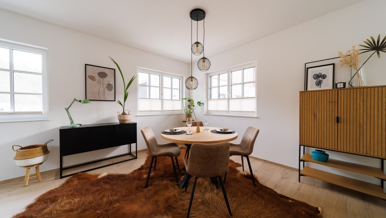 Apartment Wackelstein, © Göllitzhof Modernes Esszimmer mit rundem Tisch, vier Stühlen, Fellteppich und minimalistischer Dekoration.