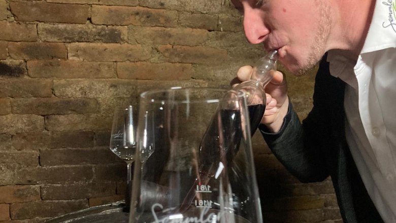 Winzerhof Semmler, © Winzerhof Semmler Ein Mann probiert Wein aus einer Pipette in einem Weinkeller.