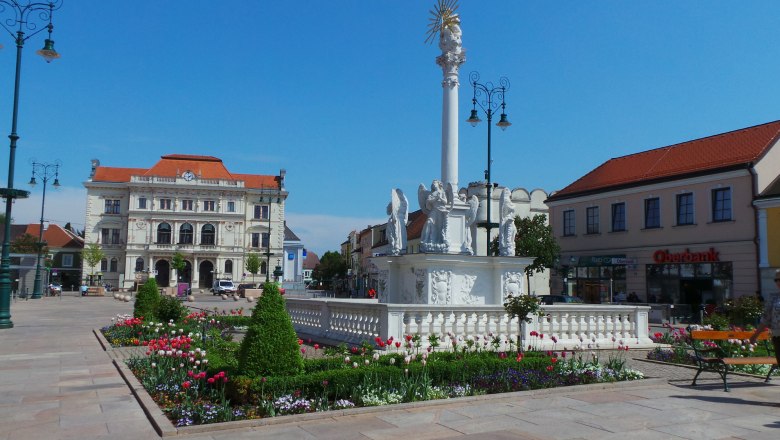 td-hauptplatz-mit-bezirksberichtzehetmayer, © DNÖ Zehetmayer Hauptplatz mit barocker Säule und Blumenbeeten, im Hintergrund ein historisches Gebäude.