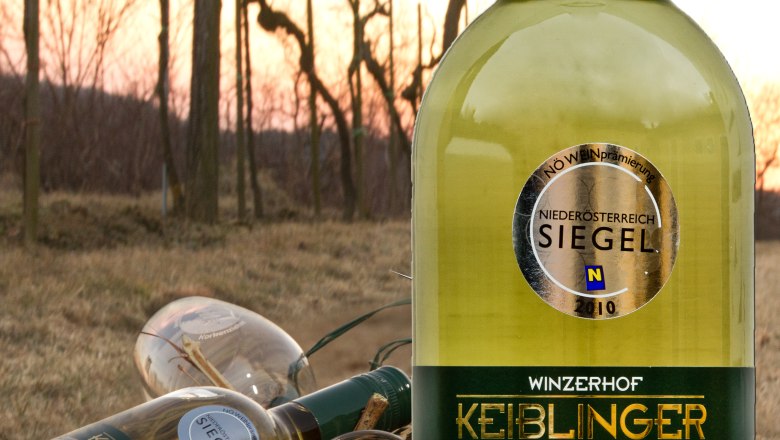 Keiblinger Wein, © Winzerhof Keiblinger Weinflasche Keiblinger im Vordergrund, Weinberge im Hintergrund.