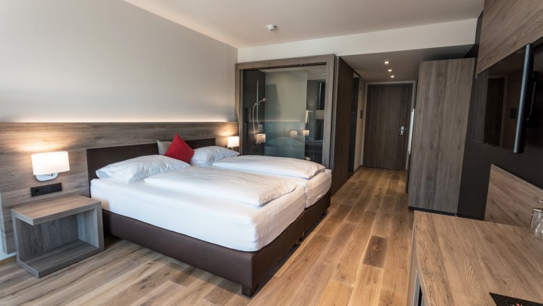 Zimmerbeispiel Weinlodge mit Holzausstattung, © KASTNER NEW MEDIA - kastner.tv Modernes Hotelzimmer mit Doppelbett, Holzboden und Glasdusche.