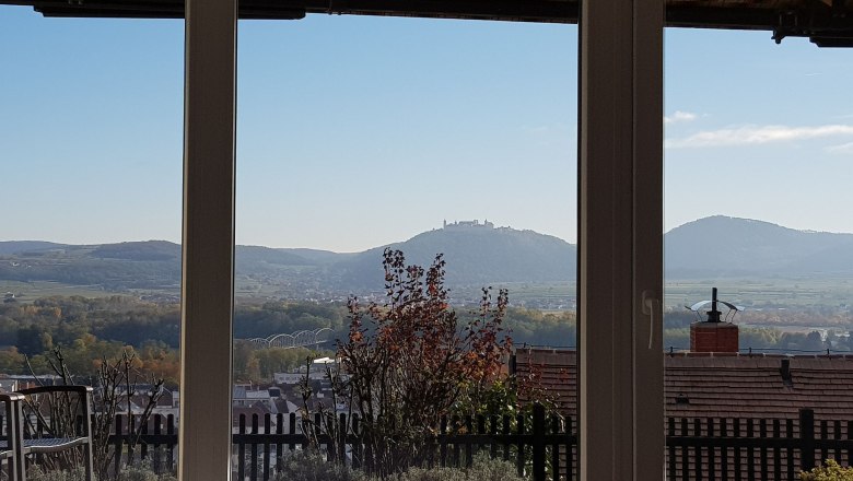 Aussicht nach Göttweig, © Familie Gföhler Blick aus einem Fenster auf eine hügelige Landschaft mit einem Kloster auf einem Hügel im Hintergrund.