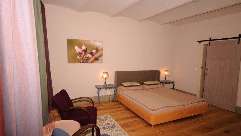 Geniesserzimmer - 4, © Franz Böck Gemütliches Schlafzimmer mit Doppelbett, zwei Nachttischen mit Lampen, zwei Sesseln und einem Bild an der Wand.