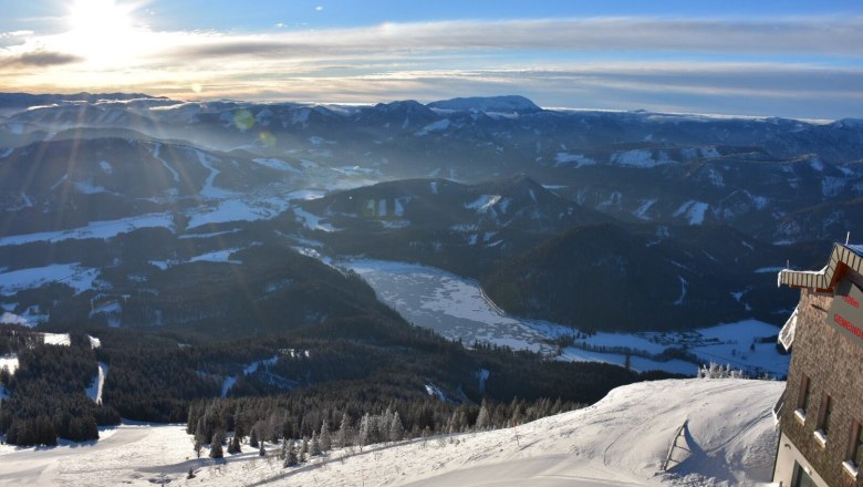 Traumhafte Ausblicke, © Gemeindalpe Mitterbach Winterlandschaft mit schneebedeckten Bergen und dem gefrorenen Erlaufsee im Sonnenuntergang.