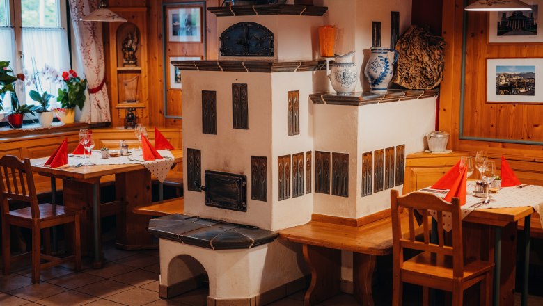 Heimelige Stube, © Niederösterreich Werbung/Daniela Führer Gemütliche Stube mit Kachelofen, Holzmöbeln und gedeckten Tischen.