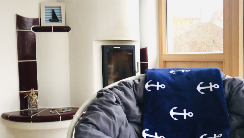 Kachelofen im gemütlichen Wohnzimmer, © Foto: Eva Zwirner Gemütliches Wohnzimmer mit Kachelofen und Sessel.