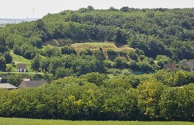 Der Hausberg von Gaiselberg ist im Gelände eindrucksvoll zu sehen, © Peter Ableidinger / Archiv Krahuletz-Museum Landschaft mit bewaldetem Hügel und Häusern im Vordergrund.