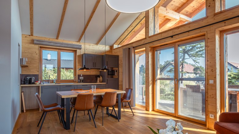 Kittenberger Chalets am Gartensee, © Niederösterreich Werbung / Maximilian Pawlikowsky Innenansicht eines modernen Chalets mit Holzbalken, Esstisch und großen Fenstern.