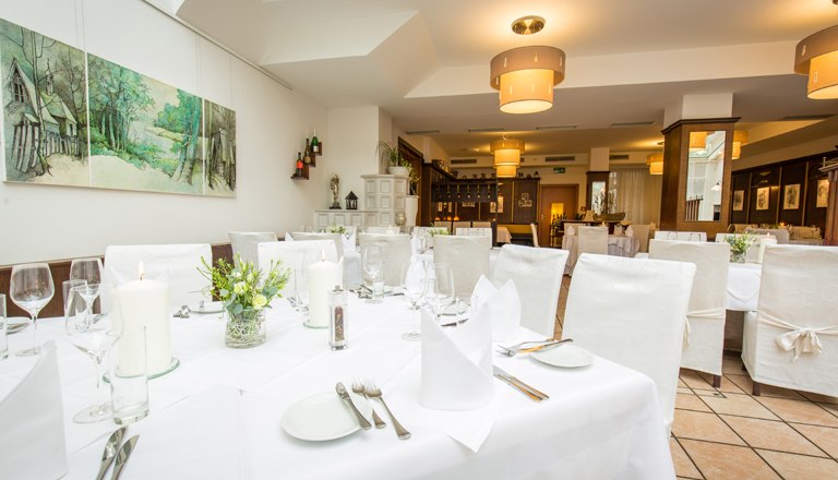 Wintergarten Restaurant, © flotographix Der Wintergarten mit einem gedeckten Tisch und weißen Stühlen.