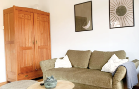 TDR-Chalet Wienerwald-stilvolles Wohnzimmer, © Obermeier green sofa in room with wooden floor and wardrobe