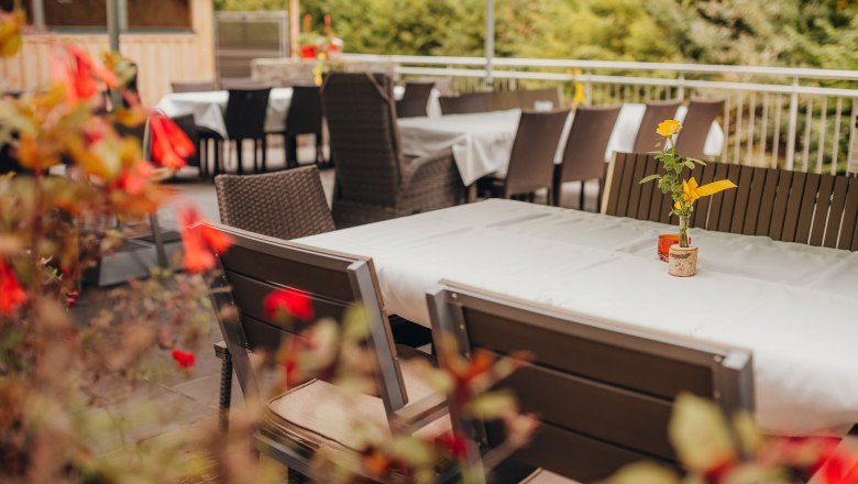 Der Platz im Gastgarten, © Niederösterreich Werbung/Daniela Führer Ein leerer Gastgarten mit gedeckten Tischen und Blumen in Vasen.