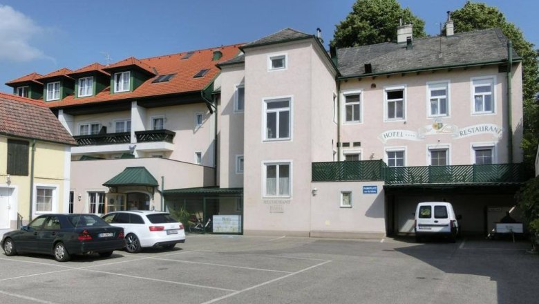 Außenansicht, © Hotel VinoQ Außenansicht eines Hotels mit Parkplatz und Autos.