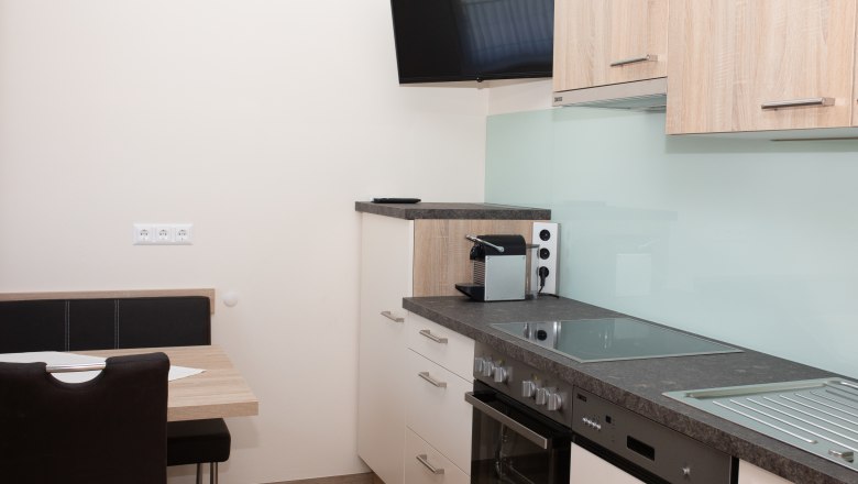 Vollausgestattete Küche mit Fernseher und WLAN, © Familie Schwalm Moderne Küche mit Herd, Spüle, Kaffeemaschine und Wandfernseher.