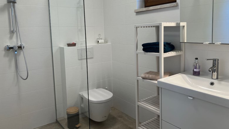 Ferienhaus Stixneusiedl, Bad, © Karoline Wolfger Modernes Badezimmer mit Dusche, Waschbecken und Regal.