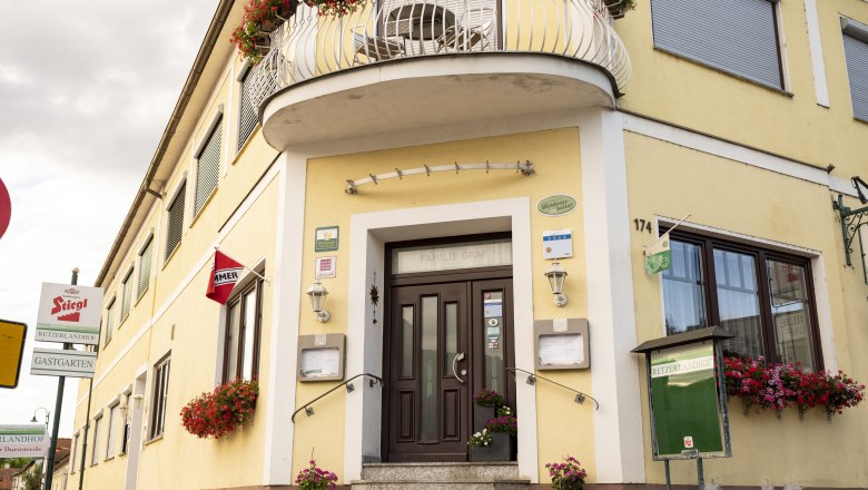 Wirtshaus mit 4-Sterne –Gästezimmern, © Niederösterreich Werbung/Michael Reidinger Gelbes Wirtshaus mit Blumen und Schildern, darunter "Stiegl" und "Retzerlandhof".