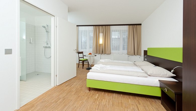 Stadthotel Waidhofen, © Stadthotel Waidhofen Modernes Hotelzimmer mit Doppelbett, Holzboden und angrenzendem Badezimmer.
