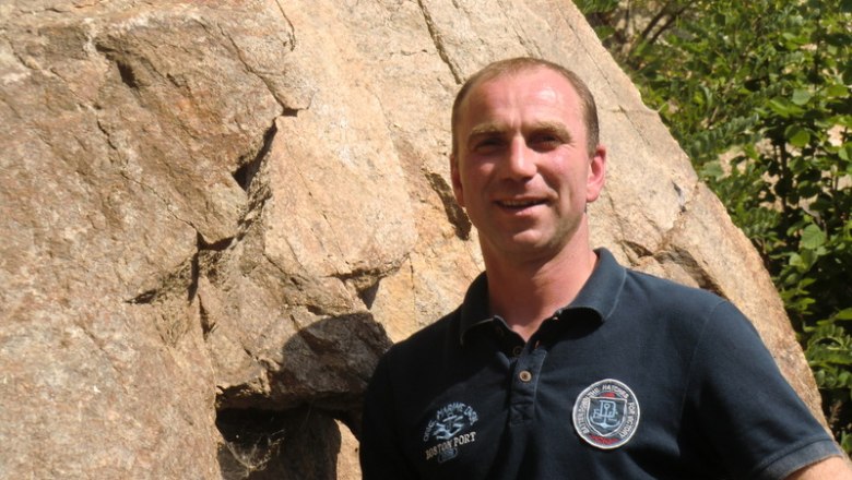 Winzer Leo Maurer, © Weingut Maurer Ein Mann steht vor einem großen Felsen und lächelt in die Kamera.