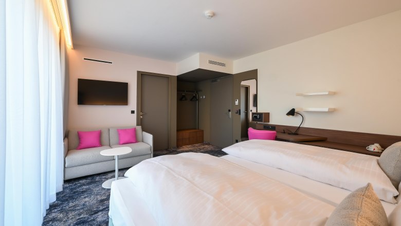 Suite mit Blick zum Schneeberg, © Philipp Blickfang Moderne Hotelsuite mit Doppelbett, Sofa, Fernseher und Schreibtisch.